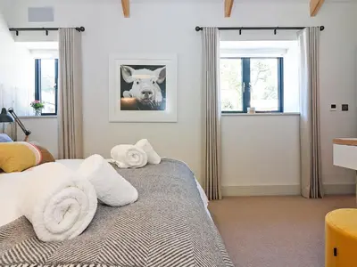 a bedroom with a bed with towels on it at Pig House, Boskensoe Barns in Helford Passage