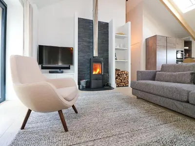 a living room with a couch and a chair and a fireplace at Pig House, Boskensoe Barns in Helford Passage