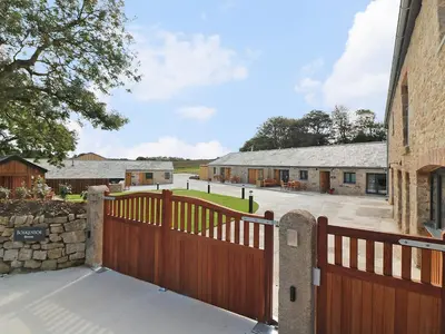 a wooden fence with a gate in front of a building at Long House, Boskensoe Barns in Helford Passage
