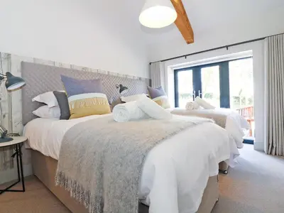 two beds in a bedroom with white and blue at Long House, Boskensoe Barns in Helford Passage