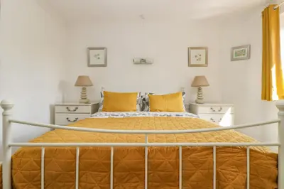 a bedroom with a large bed with orange sheets and pillows at Silverwell Forge in Chacewater