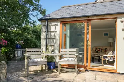 a greenhouse with two chairs and a table in it at Silverwell Forge in Chacewater