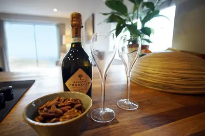 a bottle of wine and two wine glasses on a table at Ocean Views 3 in Newquay