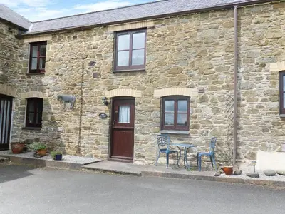 a stone house with two chairs and a table outside at The Old Granary in Launceston