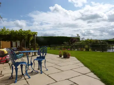 a patio with a table and chairs and a lawn at The Old Granary in Launceston