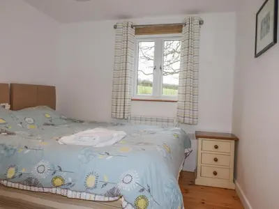 a bedroom with a bed and a window at Vine Cottage in Saint Ewe
