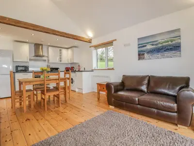 a living room with a leather couch and a table at Vine Cottage in Saint Ewe