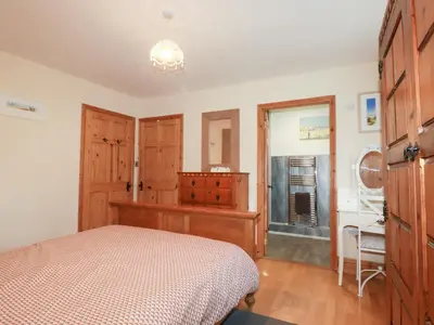 a bedroom with a bed and a dresser at Kingfisher Barn in Liskeard