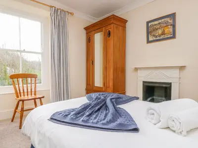 a bedroom with a bed and a chair and a fireplace at Goshen Farm in St. Agnes