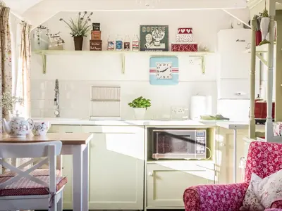 a kitchen with white cabinets and a table and a chair at The Snug in Bugle