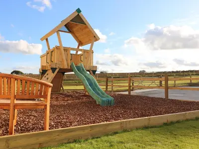a playground with a slide and a bench at The Stable, Boskensoe Barns in Falmouth