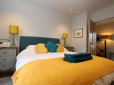 a bedroom with a bed with yellow and blue pillows at The Snug in Grampound