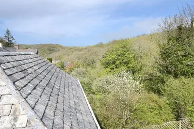 an old roof of a building with a hill in the background at Tower House in Boscastle