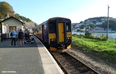 a train pulling into a train station with people waiting at Sand Dune in Looe