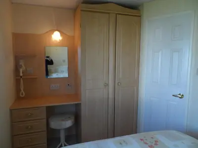 a bedroom with a bed and a desk and a closet at Luxury Mobile Home near Perranporth situated on a quiet farm in Truro