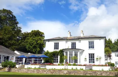 a white house with a fence and a yard at Penmere Manor Hotel in Falmouth