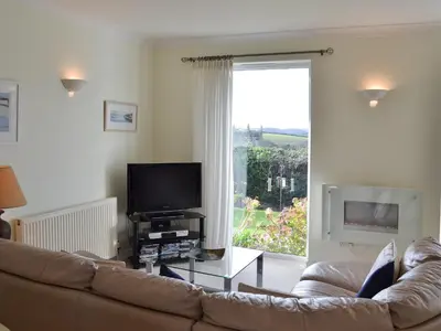 a living room with a couch and a large window at Moonrakers in Ruan Lanihorne