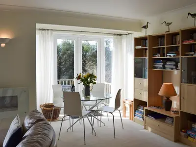 a living room with a table and a window at Moonrakers in Ruan Lanihorne