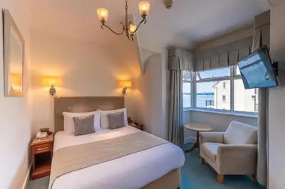a hotel room with a bed and a chair at The Royal Duchy Hotel in Falmouth