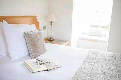 a book and glasses sitting on top of a bed at The Royal Duchy Hotel in Falmouth