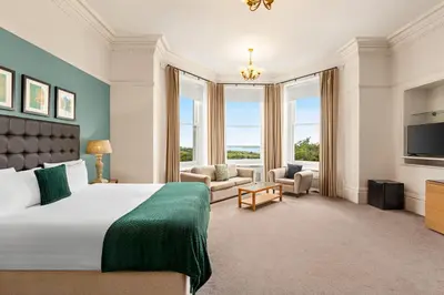 a bedroom with a large bed and a large window at Trenython Manor Resort in Fowey
