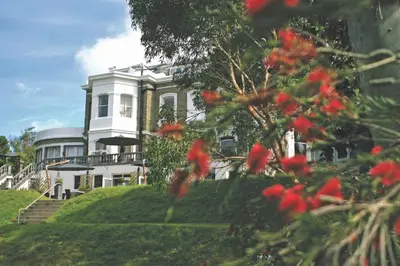 a large white house on a hill with red flowers at Trenython Manor Resort in Fowey