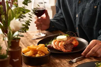 a table with a plate of food and a glass of wine at Harbour Inn in Porthleven