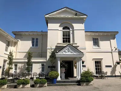 a large white building with chairs in front of it at Penventon Park Hotel in Redruth