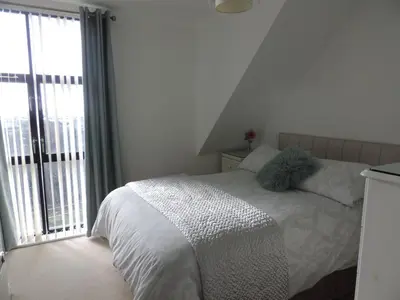 a bedroom with a bed and a large window at Sea Breeze Apartment in St Austell