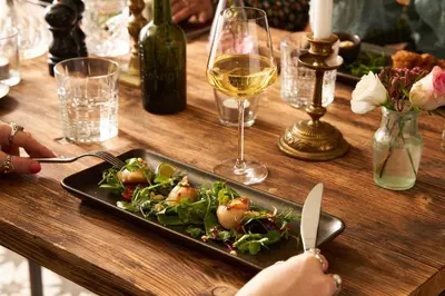 a table with a plate of food and a glass of wine at Pier House in St Austell