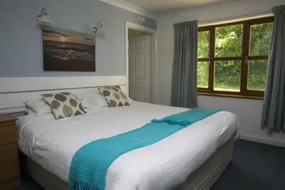 a bedroom with a bed with a blue blanket on it at Trethorne Hotel & Golf Club in Launceston