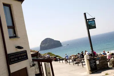 a group of people sitting at tables on the beach at Port William Inn in Tintagel