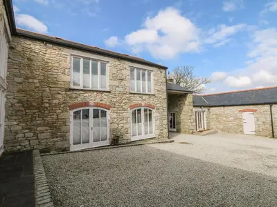 a stone house with white doors and a driveway at Argal in Penryn