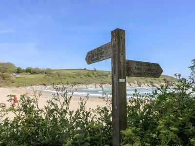 a wooden sign on a beach with the ocean at Willow in Falmouth