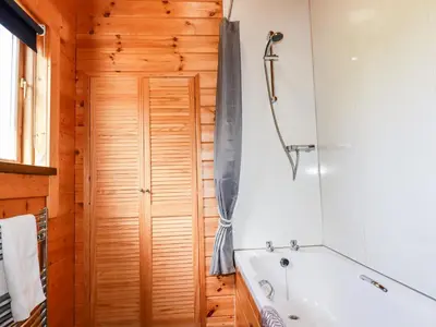 a bathroom with a tub and a wooden door at Maple Lodge in Bodmin