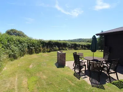 a patio with a table and chairs in a yard at Maple Lodge in Bodmin