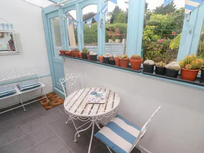 a balcony with a table and chairs and potted plants at 2 The Cottages in Ludgvan