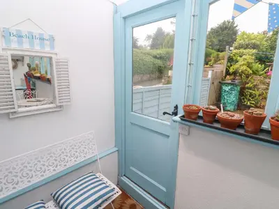 an open door to a balcony with potted plants at 2 The Cottages in Ludgvan