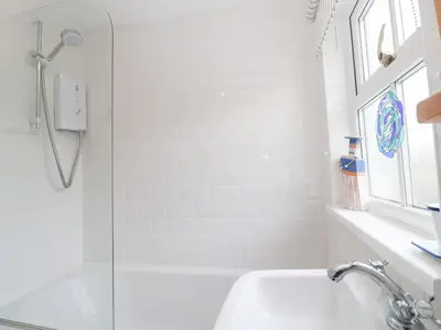 a white bathroom with a shower and a sink at 2 The Cottages in Ludgvan