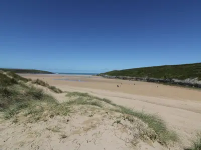 a beach with people walking on the sand at Crantock Bay House in Crantock