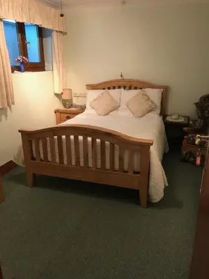 a bedroom with a large bed with white sheets and pillows at Orchard Manor in Probus
