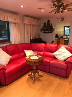 a red couch in a living room with a table at Orchard Manor in Probus