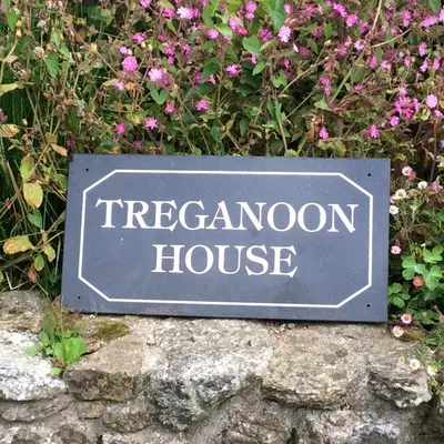 a sign for a treasonon house in front of flowers at Treganoon House, Lanlivery in Bodmin