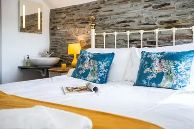 a bedroom with a white bed with blue pillows at The Olde Malthouse Inn in Tintagel