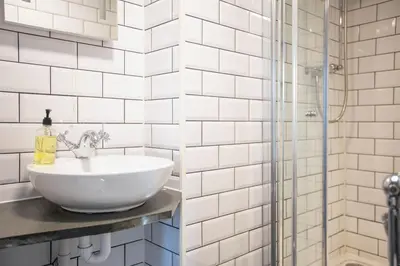 a white bathroom with a sink and a shower at The Olde Malthouse Inn in Tintagel