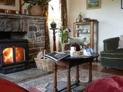 a living room with a fireplace and a coffee table at Lower Tresmorn Farmhouse in Crackington Haven