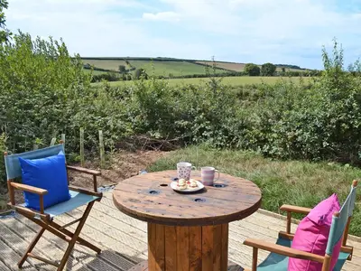 a wooden table with two chairs and a table with a drink at The Wool Shed in Saint Ewe