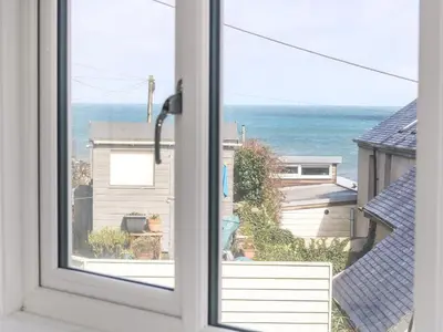 an open window with a view of the ocean at Cockle Island Cottage in Porthallow