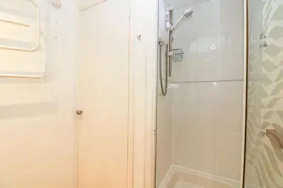 a shower with a glass door next to a bathroom at Cockle Island Cottage in Porthallow