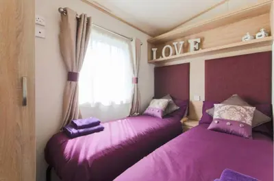 two beds in a room with purple sheets at Blenheim, Padstow in Padstow